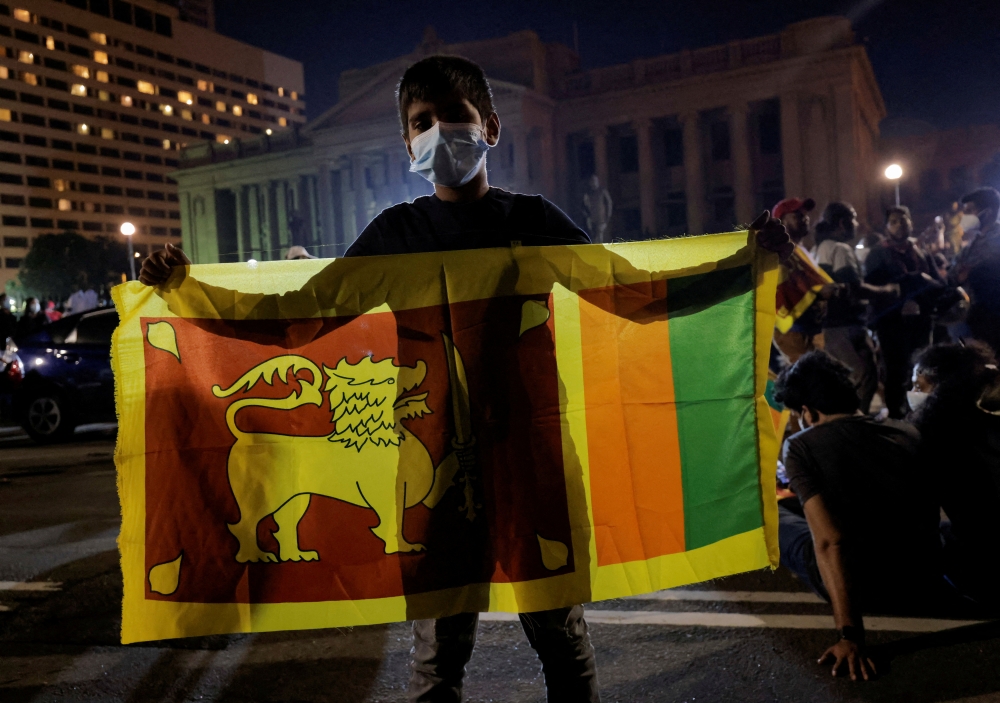 A boy holds a Sri Lankan national flag in front of the Presidential Secretariat during a protest against Sri Lankan President Gotabaya Rajapaksa, amid the country's economic crisis, in Colombo, Sri Lanka, April 10, 2022. REUTERS/Dinuka Liyanawatte