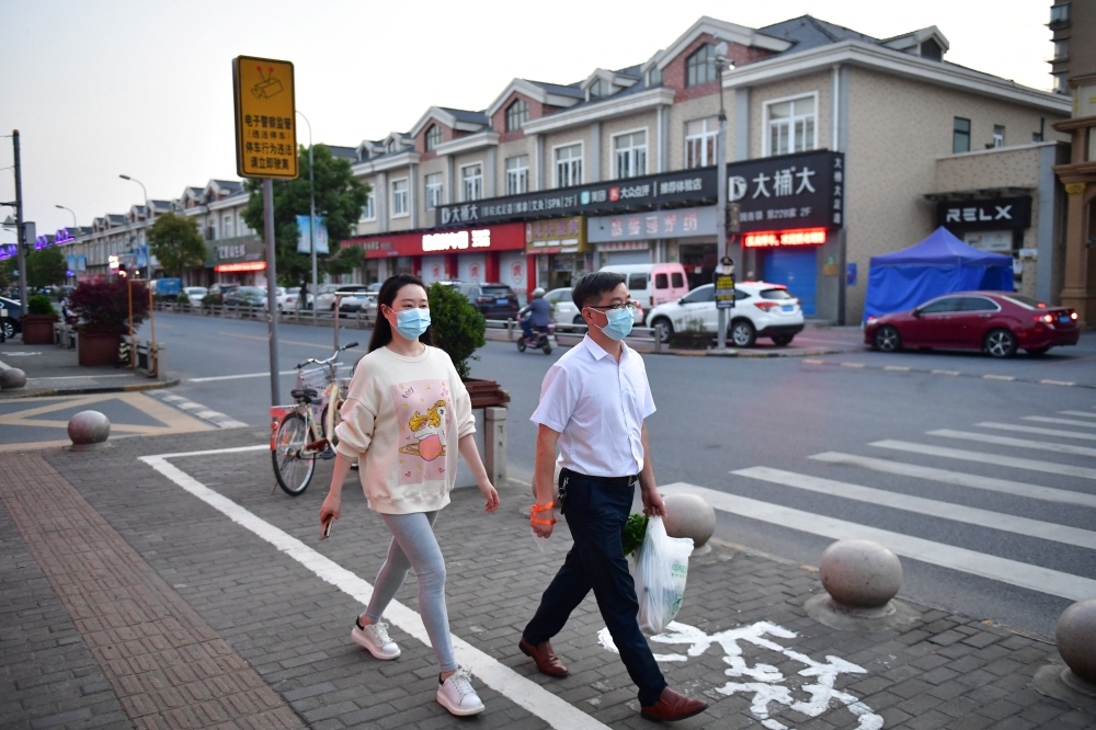 Residents walk on a street in Fengjing town of Jinshan district, as the city eases the lockdown in some areas amid the coronavirus disease (COVID-19) outbreak, in Shanghai, China April 11, 2022. Picture taken April 11, 2022. 