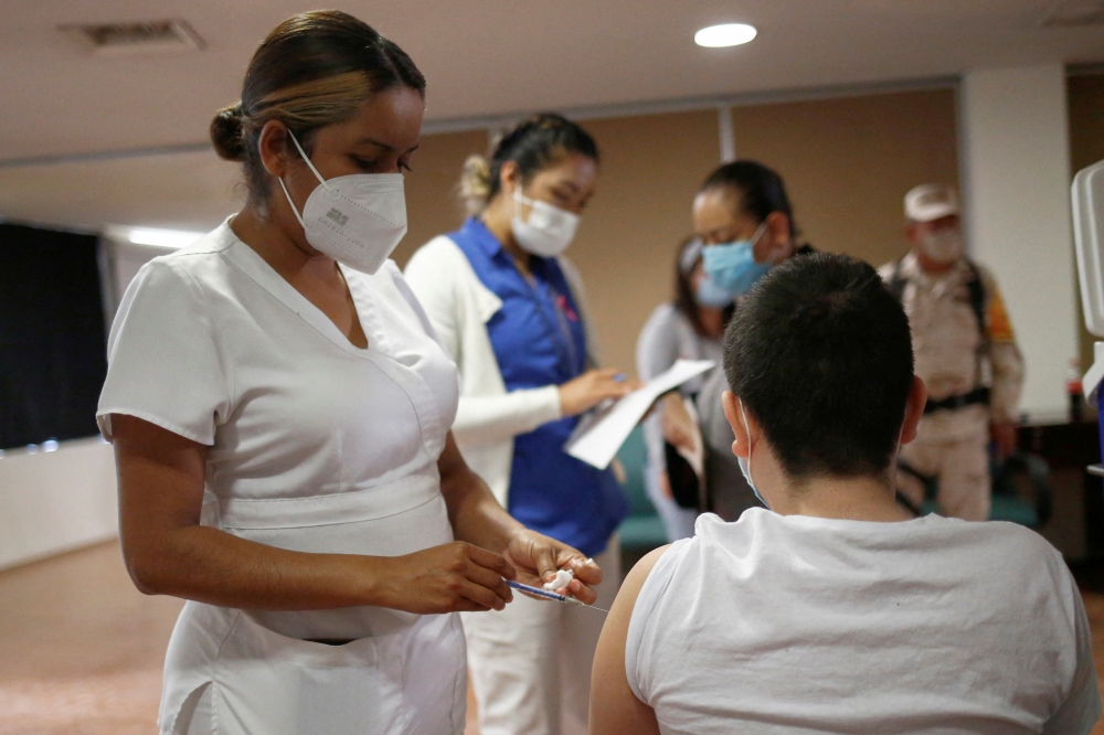 A child receives a dose of the Pfizer-BioNTech coronavirus disease (COVID-19) vaccine during a vaccination program for minors between the ages of 12 to 17 with underlying medical conditions or disability at a hospital in Ciudad Juarez, Mexico October 19, 2021. REUTERS/Jose Luis Gonzalez/File Photo