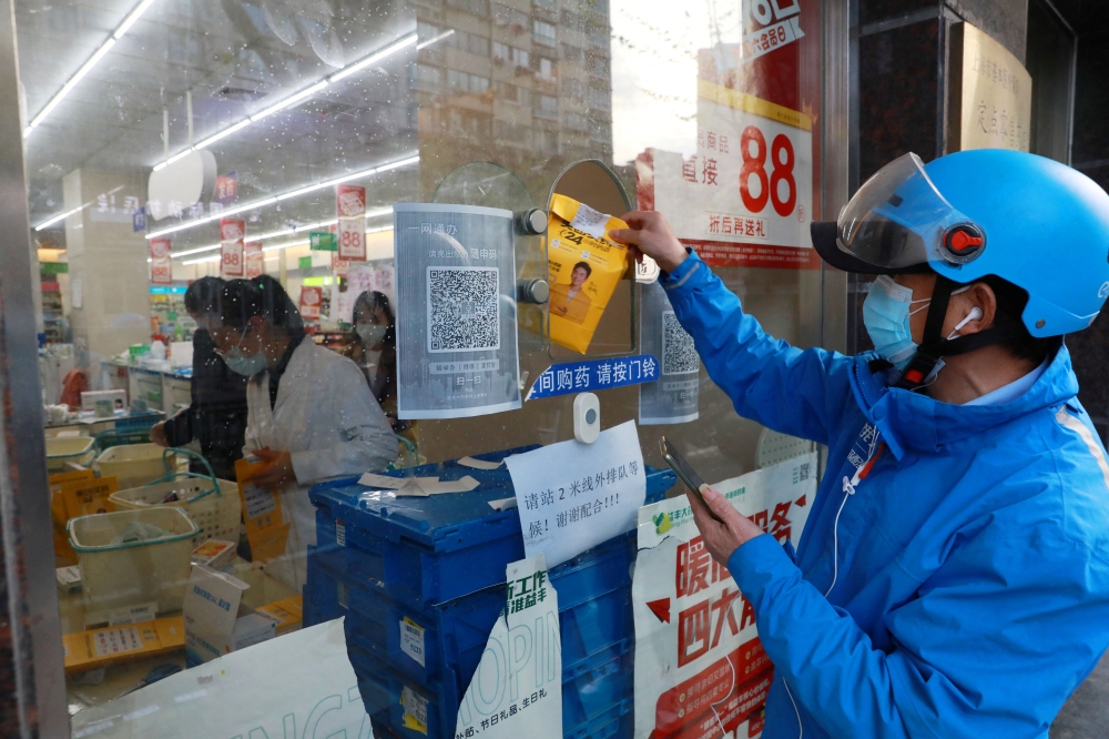 A delivery worker picks up a medicine order from a pharmacy in Huangpu district, amid the coronavirus disease (COVID-19) outbreak in Shanghai, China April 17, 2022. China Daily via Reuters