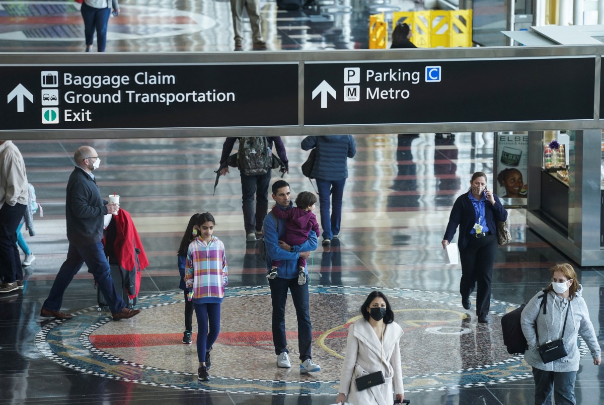 A mix of masked and unmasked travelers make their way through Ronald Reagan Washington National Airport after the Biden administration announced it would no longer enforce a U.S. coronavirus disease (COVID-19) mask mandate on public transportation, following a federal judge's ruling that the 14-month-old directive was unlawful, in Arlington, Virginia, U.S., April 19, 2022. REUTERS/Kevin Lamarque
