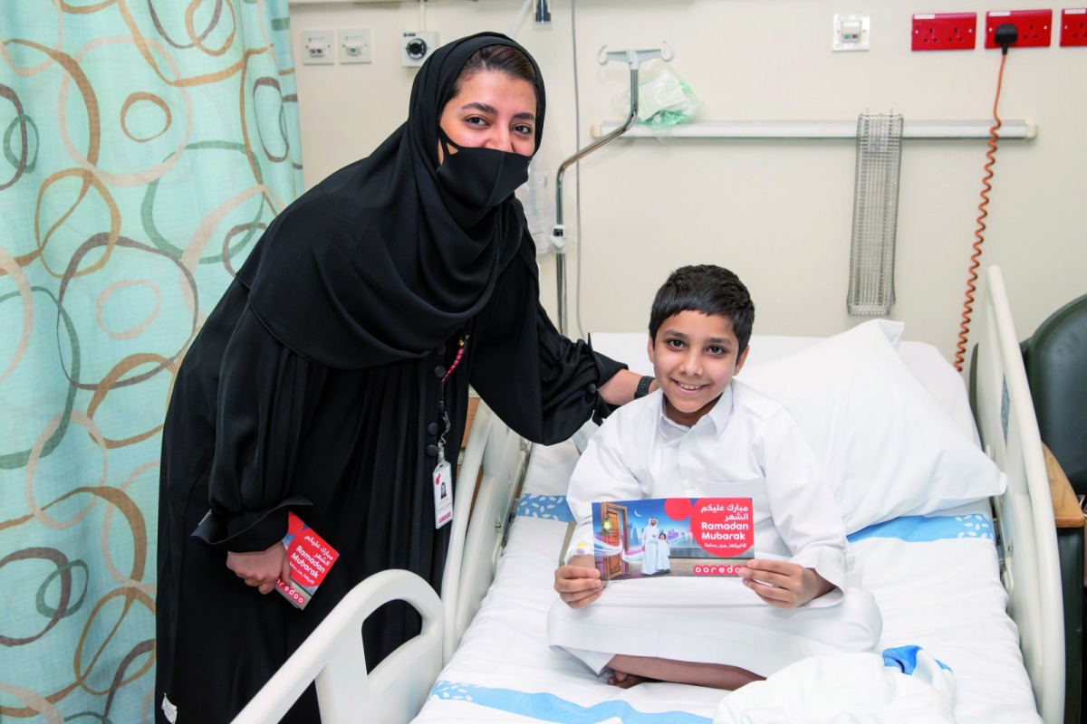 Ooredoo staff volunteers distributing gift vouchers to young patients at Hamad Hospital.