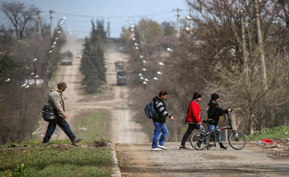 People cross a road in the course of Ukraine-Russia conflict in the southern port city of Mariupol, Ukraine April 21, 2022. REUTERS/Chingis Kondarov/File Photo