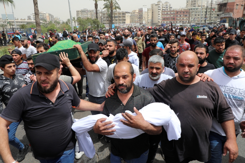 :A father holds the body of his child who died after a small dinghy carrying around 60 people sunk off the coast near the port city of Tripoli on Saturday night, during a funeral in Tripoli, Lebanon April 25, 2022. REUTERS/Mohamed Azakir
