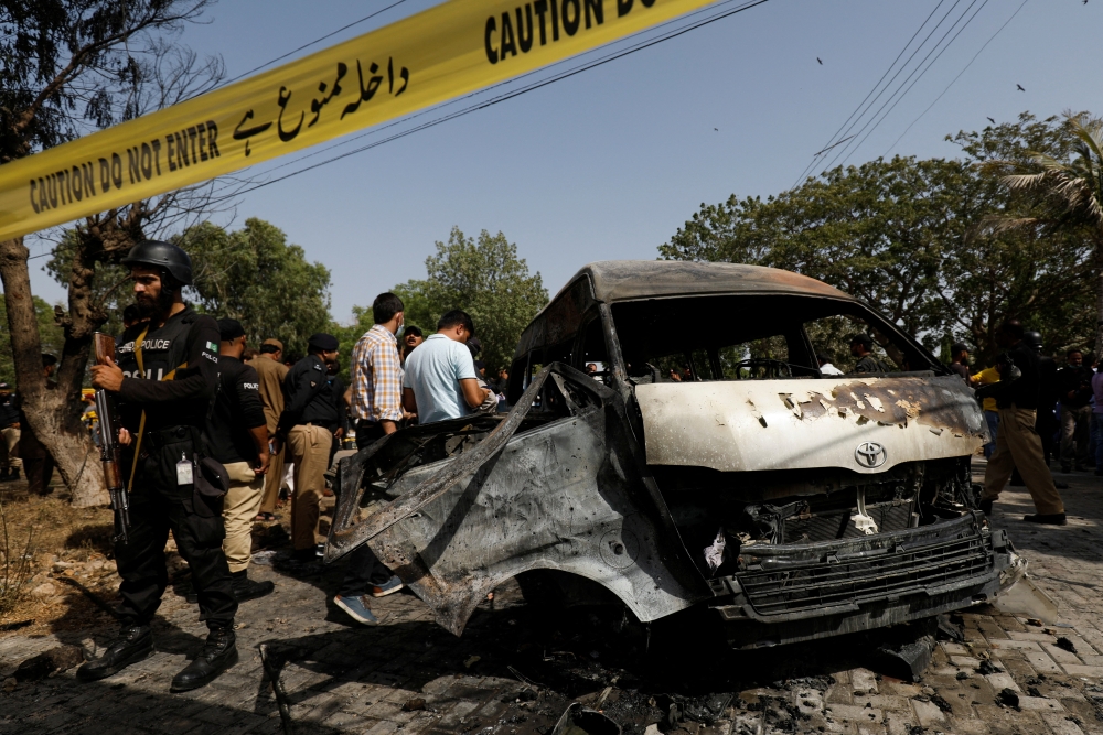 Police officers and a crime scene unit gather near a passenger van, after a blast at the entrance of the Confucius Institute University of Karachi, Pakistan April 26, 2022. Reuters /Akhtar Soomro