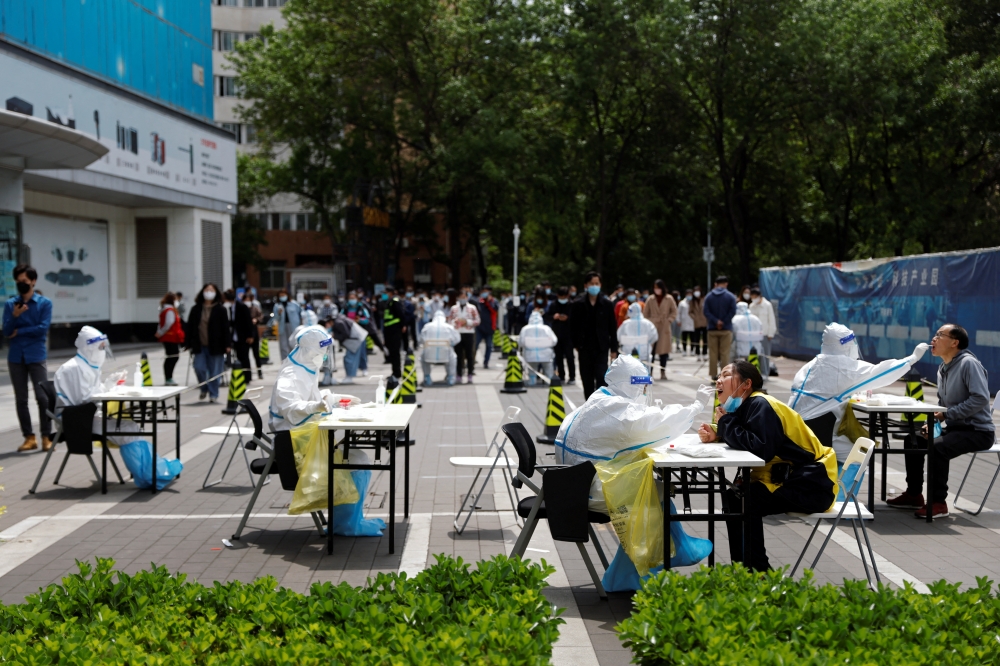 Medical workers in protective suits collect swabs from residents at a makeshift nucleic acid testing site amid the coronavirus disease (COVID-19) outbreak in Beijing, China April 28, 2022. Reuters/Carlos Garcia Rawlins