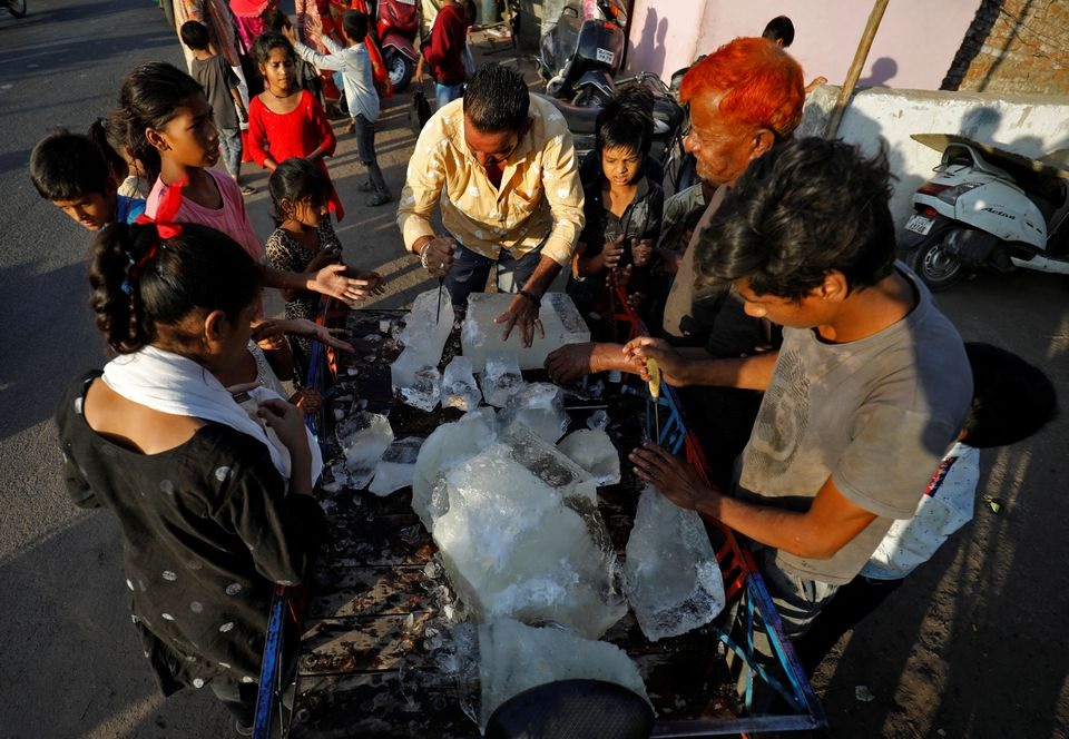 A man breaks a block of ice to distribute it among the residents of a slum during hot weather in Ahmedabad, India, April 28, 2022. REUTERS/Amit Dave


