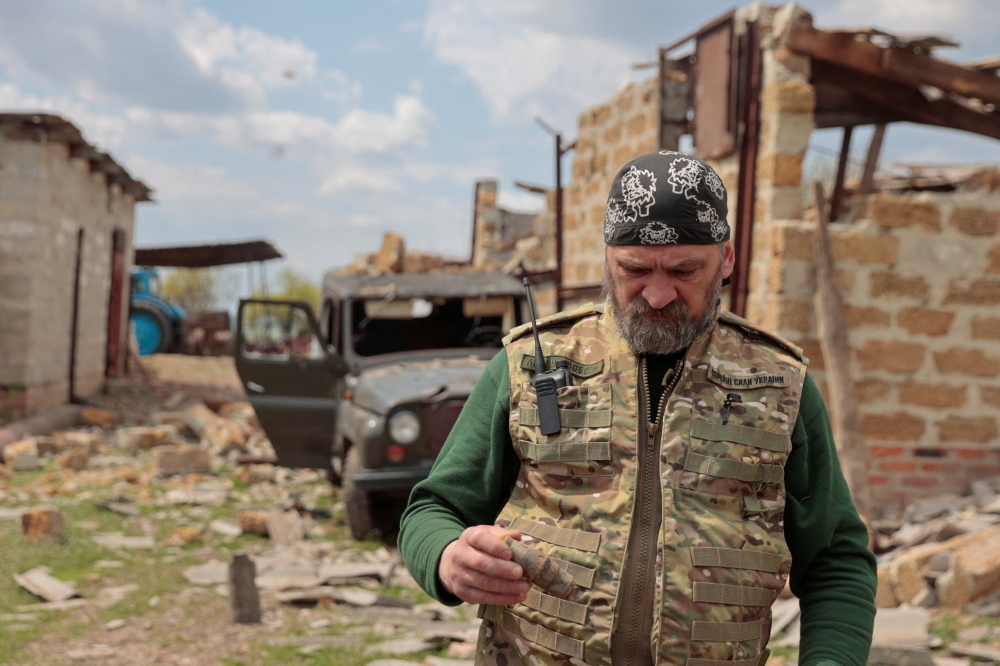 Andrii, a serviceman of the Ukrainian Armed Forces volunteer unit Karpatska Sich, walks at a compound of a farmer enterprise, damaged during a Russian a military strike, in Kharkiv region, Ukraine May 2, 2022. Reuters/Serhii Nuzhnenko