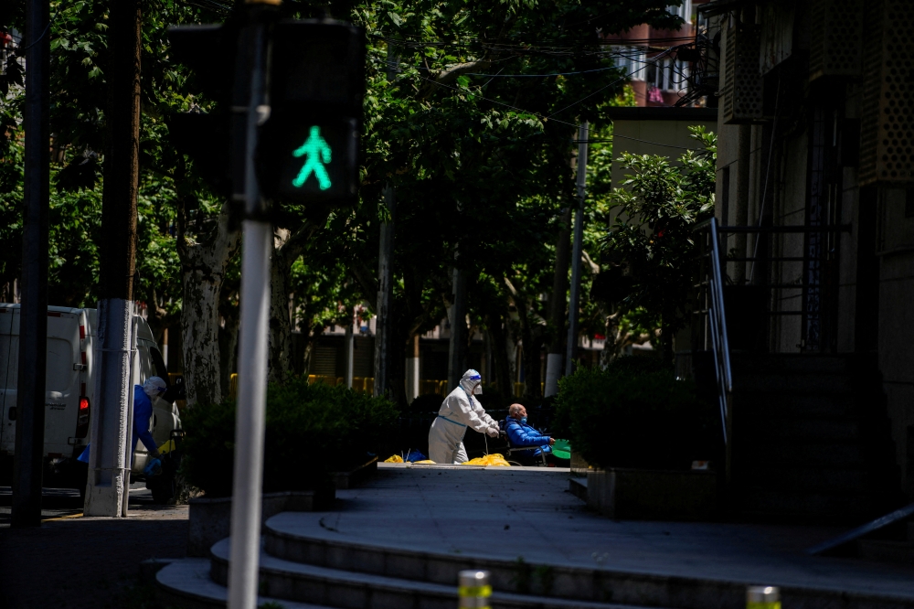 A worker in a protective suit helps an old man with a wheelchair during lockdown amid the coronavirus disease (COVID-19) pandemic, in Shanghai, China, May 5, 2022. REUTERS/Aly Song/File Photo