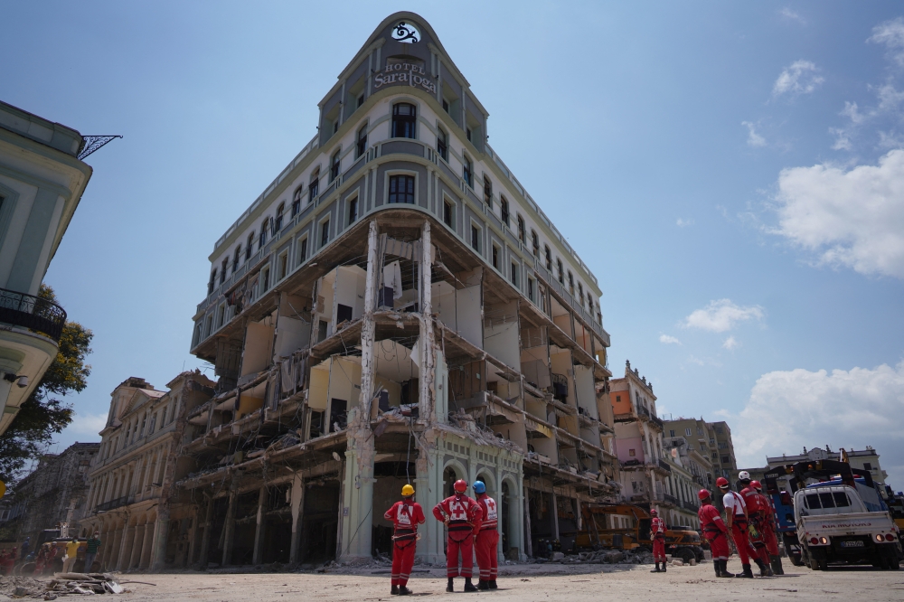 Emergency personnel stand in front of the Saratoga Hotel four days after it suffered an explosion in Havana, Cuba May 10, 2022. REUTERS/Alexandre Meneghini