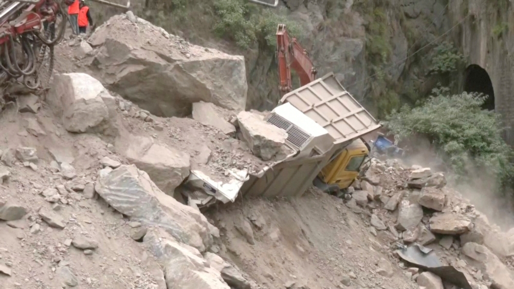 A crane removes debris from around a trapped vehicle after the collapse of a tunnel under construction in Ramban, Jammu and Kashmir, May 20, 2022, in this still image obtained from a video. ANI