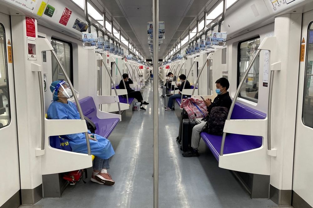 A passenger in a protective suit rides on a subway train on the first day of parts of city's subway services resumed in Shanghai, China May 22, 2022. Reuters/Brenda Goh