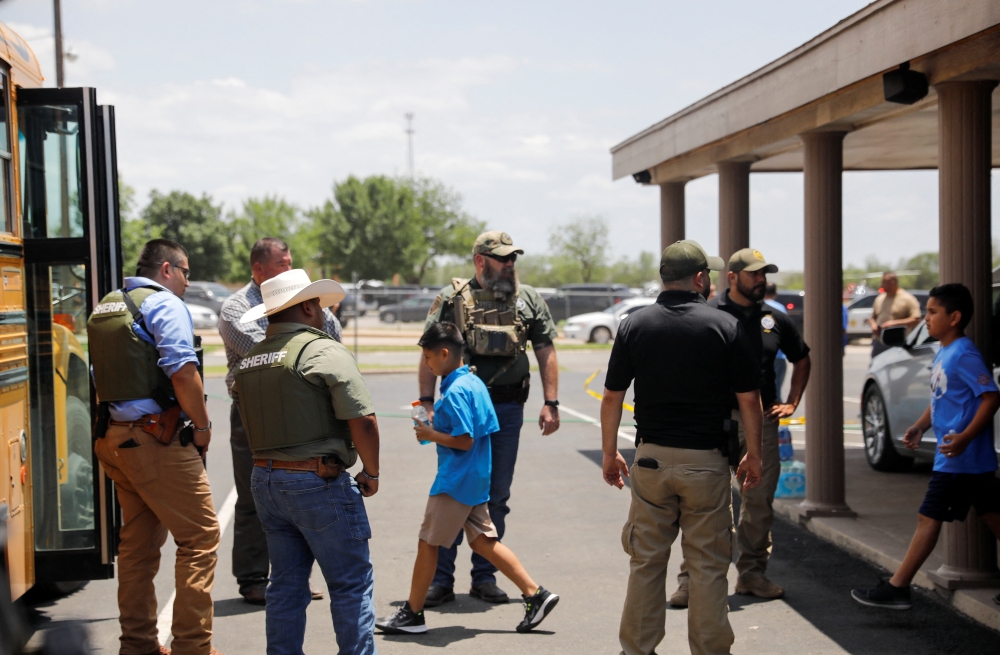 Children get on a school bus as law enforcement personnel guard the scene of a suspected shooting near Robb Elementary School in Uvalde, Texas, U.S. May 24, 2022. REUTERS/Marco Bello
