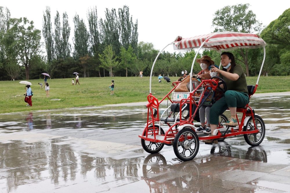 People ride a four-wheeled bike while enjoying at Sun Park on the day of its reopening after the government eased some of the restrictions, amid the coronavirus disease (COVID-19) outbreak in Beijing, China May 29, 2022. REUTERS/Carlos Garcia Rawlins