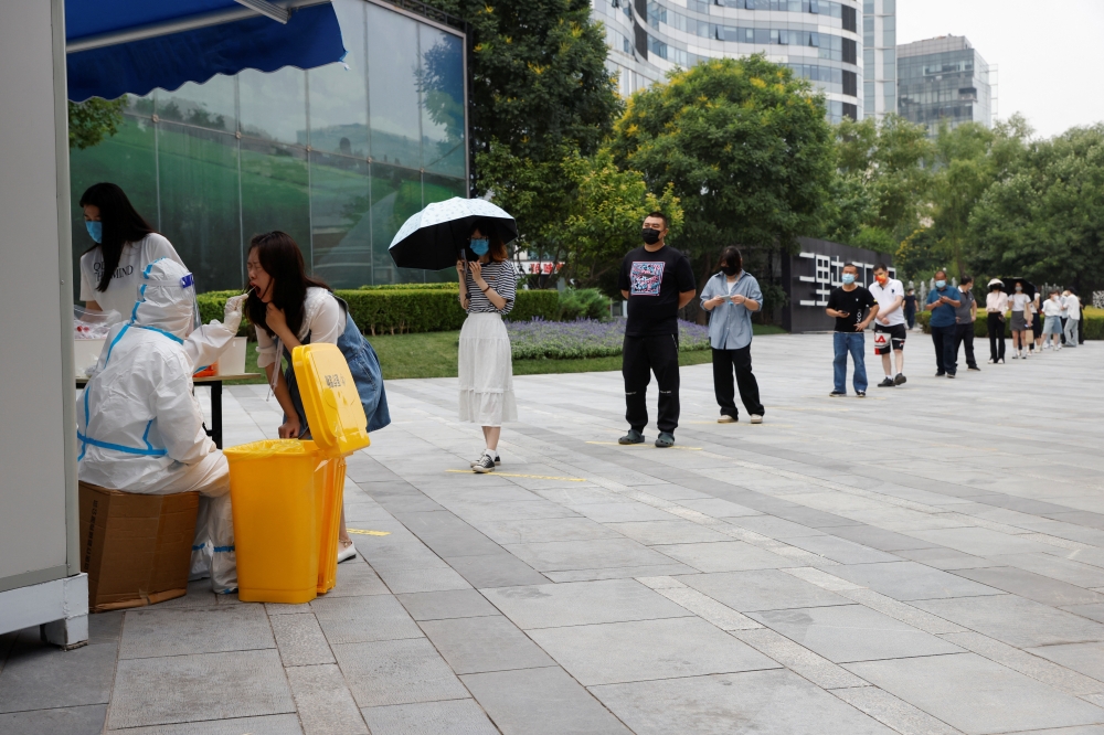 A medical worker wearing personal protective equipment (PPE) collects a swab from a resident at a mobile nucleic acid testing site amid the coronavirus disease (COVID-19) outbreak in Beijing, China June 10, 2022. Reuters/Carlos Garcia Rawlins