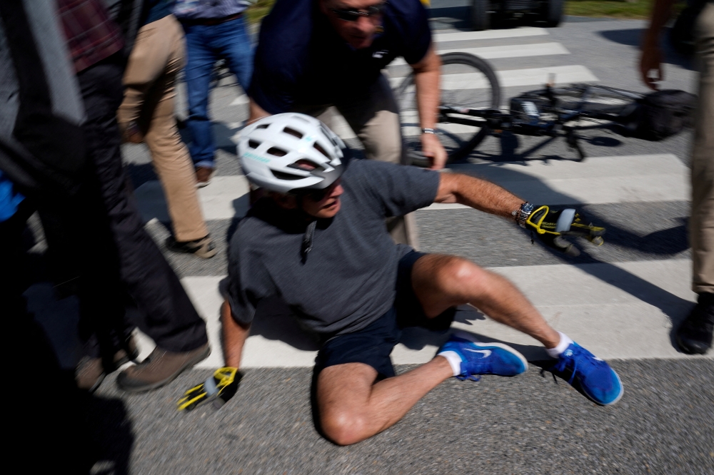 U.S. President Joe Biden falls to the ground after riding up to members of the public during a bike ride in Rehoboth Beach, Delaware, U.S., June 18, 2022. REUTERS/Elizabeth Frantz
