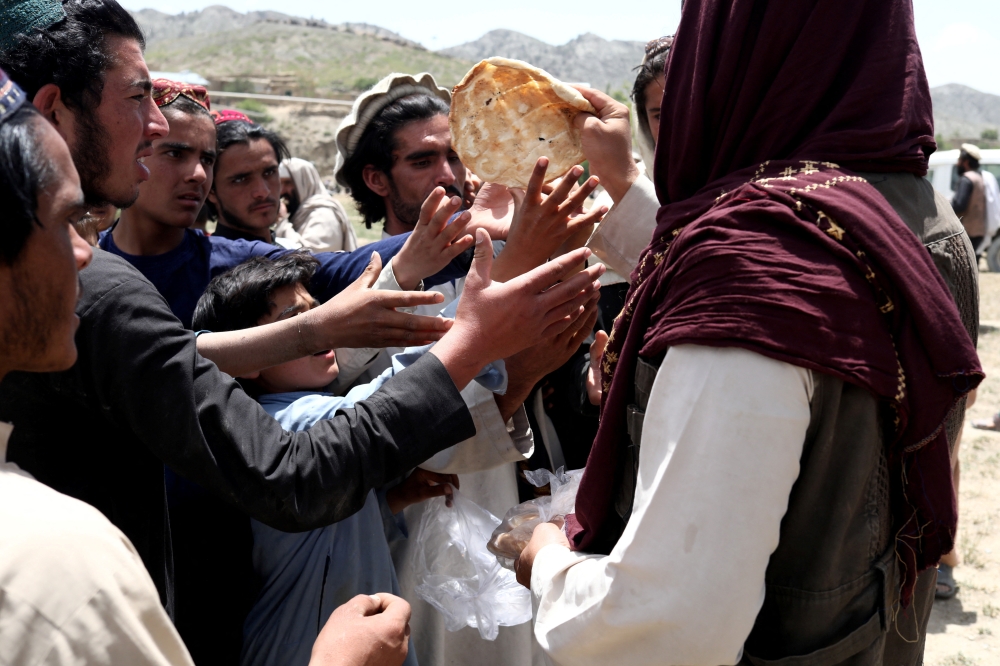 Afghan men receive bread in an area affected by an earthquake in Gayan, Afghanistan, June 23, 2022. (Reuters/Ali Khara)
 