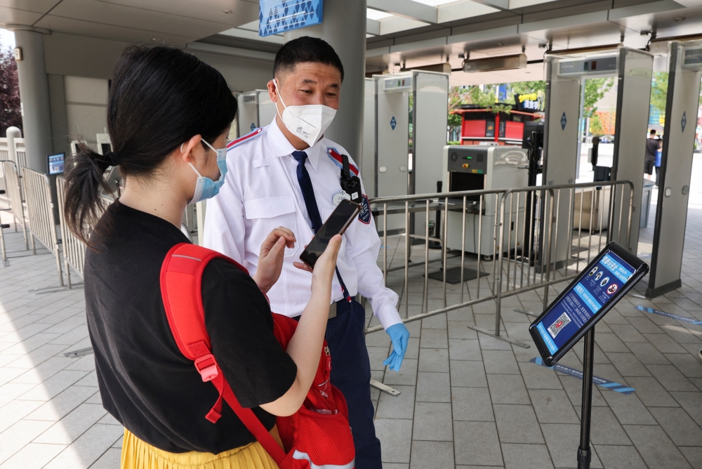 A security guard checks nucleic acid test result for a tourist at an entrance to the Universal Beijing Resort in Beijing, China June 25, 2022. Reuters/Tingshu Wang