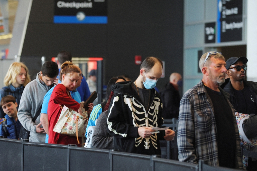 Travellers wearing masks and not wearing masks wait in line at a security checkpoint at Logan International Airport in Boston, Massachusetts, U.S., April 19, 2022. Reuters/Brian Snyder/File Photo