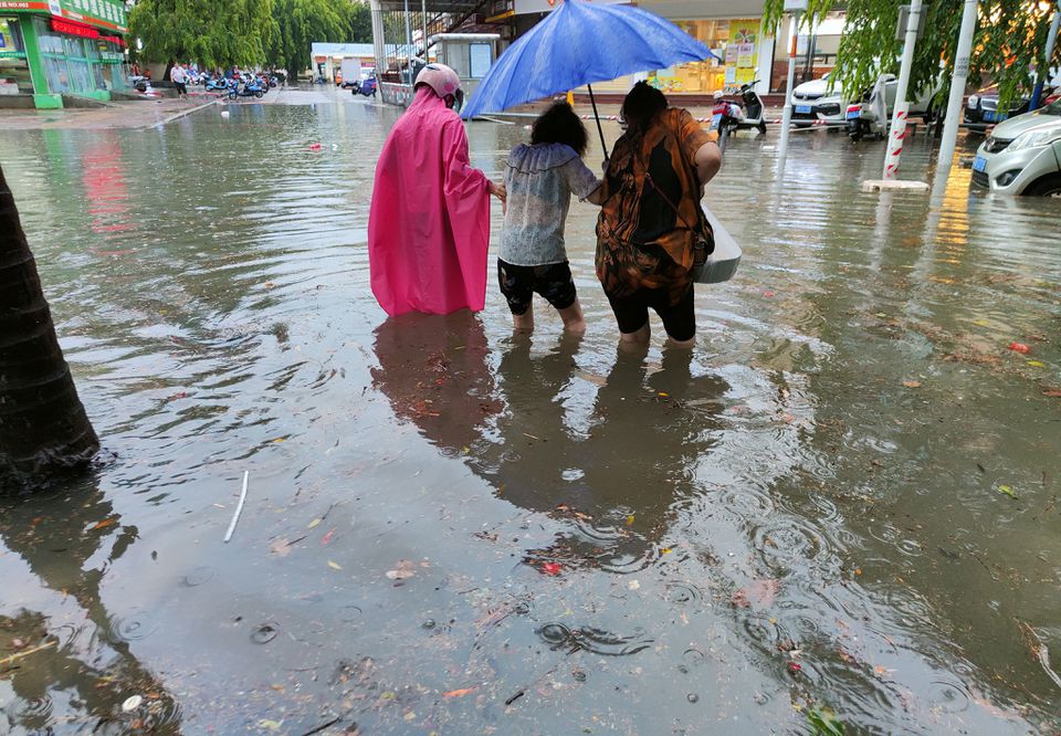 Pedestrians wade through floodwaters on a street amid heavy rainfall as Typhoon Chaba hits Sanya in Hainan province, China July 2, 2022. cnsphoto via REUTERS

