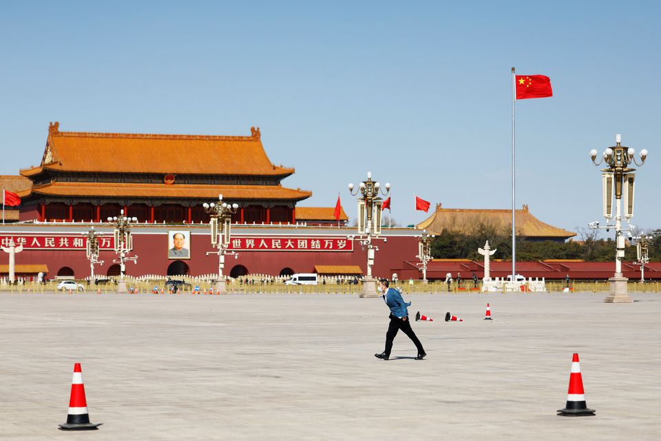 A man braving the wind walks past the Chinese flag on the Tiananmen Square, before the opening session of the Chinese People's Political Consultative Conference (CPPCC) in Beijing, China March 4, 2022. REUTERS/Carlos Garcia Rawlins