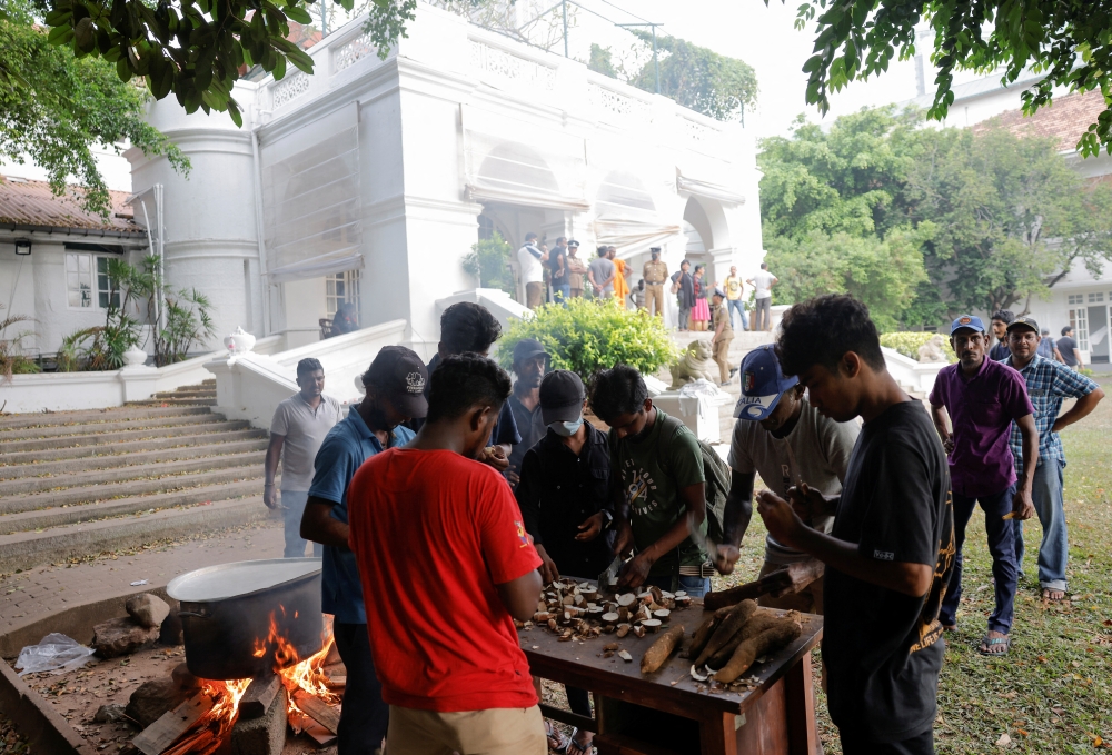 People cook in the garden of the Prime Minister's residence on the following day after demonstrators entered the building, amid the country's economic crisis, in Colombo, Sri Lanka July 10, 2022. (Reuters/Dinuka Liyanawatte)