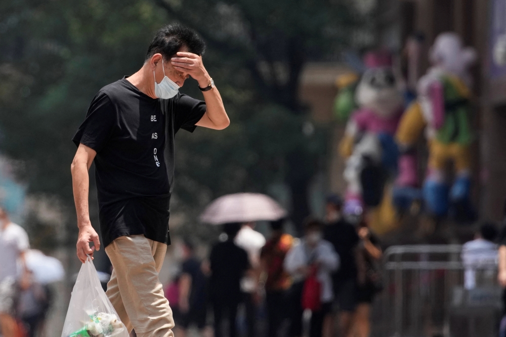 A man wearing face mask reacts on a street amid a heatwave warning, following the coronavirus disease (COVID-19) outbreak in Shanghai, China July 13, 2022. REUTERS/Aly Song