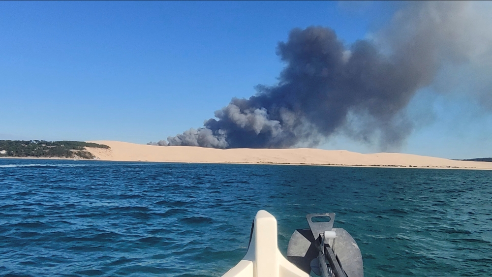 A general view shows smoke rising from the Gironde forest fires as seen from Dune de Pilat, Arcachon Bay, France July 12, 2022 in this still image obtained from a social media video. Quentin/via REUTERS