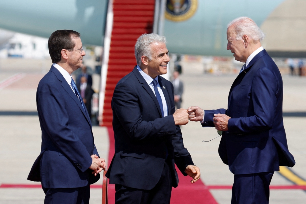 Israeli President Isaac Herzog looks on as Prime Minister Yair Lapid bumps fists with US President Joe Biden during a welcoming ceremony at Ben Gurion International Airport in Lod, near Tel Aviv, Israel, July 13, 2022. (REUTERS/Amir Cohen) 