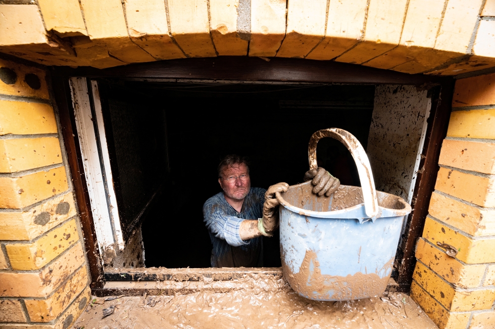 Walter Jueliger removes mud with a bucket from the cellar of a house after heavy rainfalls caused flooding of the nearby Erft river in Bad Muenstereifel, Germany July 17, 2021. REUTERS/Benjamin Westhoff