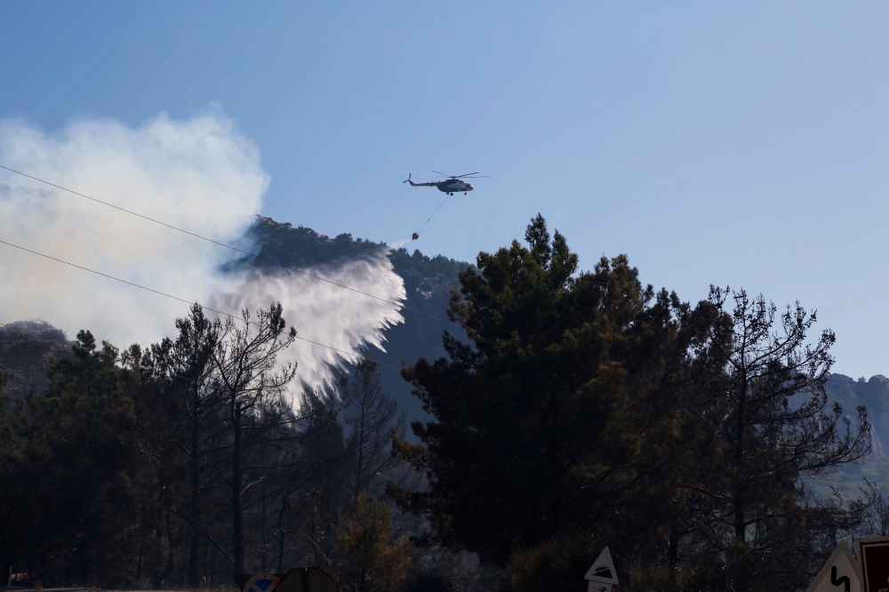 A helicopter drops water to extinguish a wildfire in Datca in Mugla province, Turkey July 14, 2022. REUTERS/Kenan Gurbuz