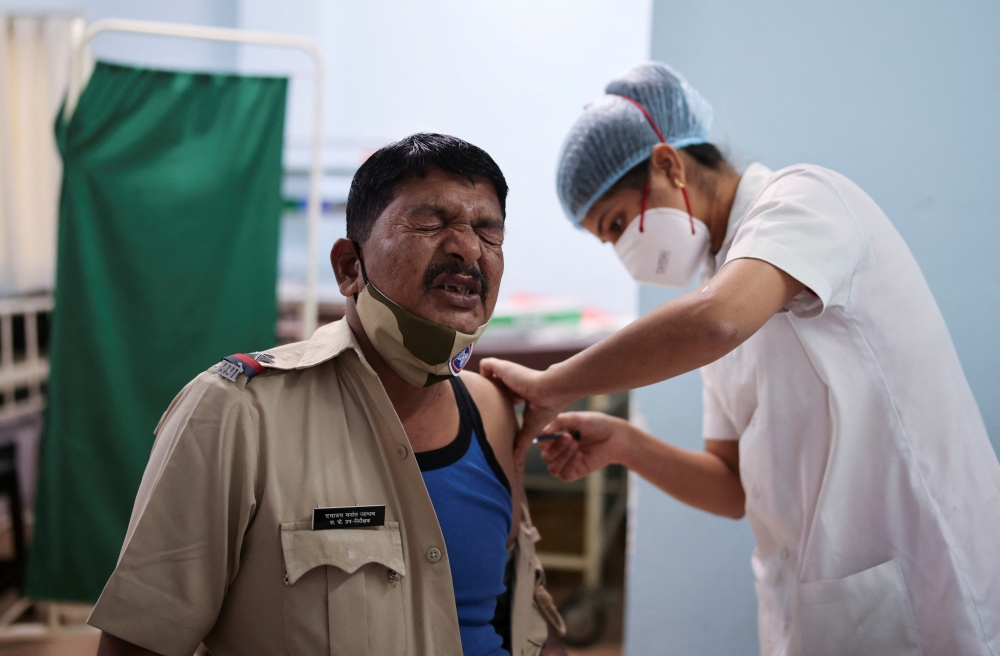 A policeman reacts as he receives a booster dose of the COVISHIELD vaccine against the coronavirus disease (COVID-19), manufactured by Serum Institute of India, at a vaccination centre in Mumbai, India, January 10, 2022. REUTERS/Francis Mascarenhas/File Photo
