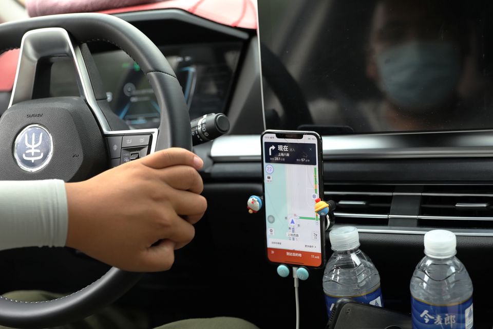 A driver of Chinese ride-hailing service Didi drives with a phone showing a navigation map on Didi's app, in Beijing, China July 5, 2021. REUTERS/Tingshu Wang

