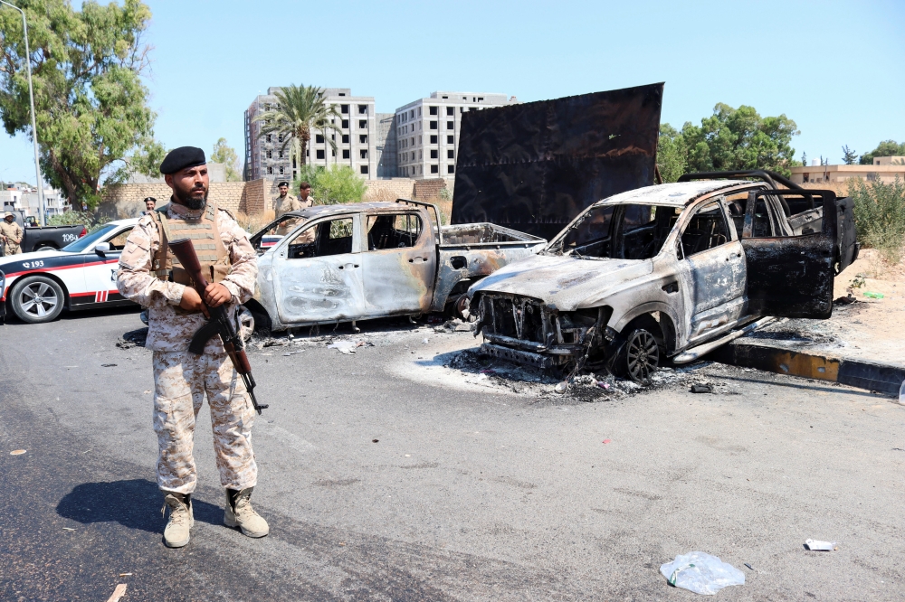 A member of the Libyan armed unit, 444 Brigade, backing the Government of National Unity (GNU) and its Prime Minister Abdulhamid al-Dbeibah, stands in front of burned vehicles in Ain Zara area in Tripoli, Libya, July 22, 2022. (REUTERS/Hazem Ahmed)