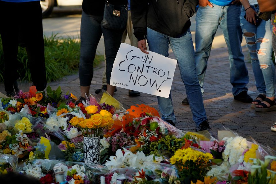 A mourner holds a sign advocating for gun control while visiting a memorial for victims of a mass shooting at a Fourth of July parade in the Chicago suburb of Highland Park, Illinois, U.S. July 7, 2022. REUTERS/Cheney Orr


