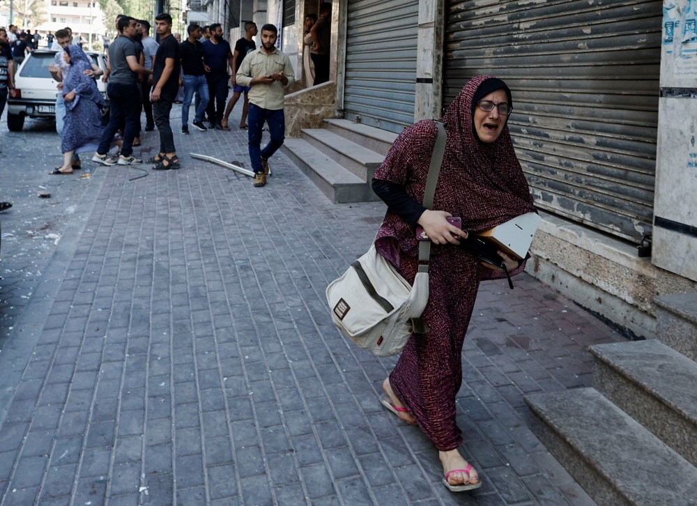 A Palestinian woman reacts as people gather at the site of an explosion in Gaza City August 5, 2022. (REUTERS/Mohammed Salem)