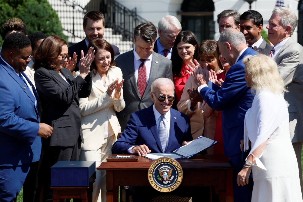 US President Joe Biden signs the CHIPS and Science Act of 2022 alongside Vice President Kamala Harris, House of Representatives Speaker Nancy Pelosi and Joshua Aviv, founder and CEO of SparkCharge, on the South Lawn of the White House in Washington on August 9, 2022. (REUTERS/Evelyn Hockstein)