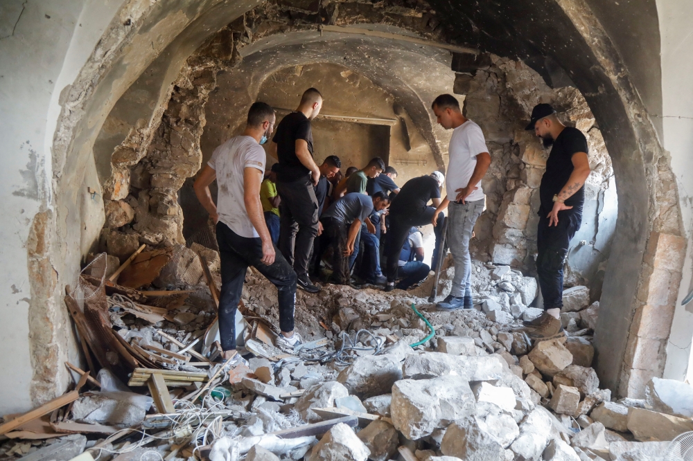 Palestinians inspect a building damaged during clashes between Palestinian militants and Israeli forces in a raid, in Nablus in the Israeli-occupied West Bank, August 9, 2022. (REUTERS/Raneen Sawafta)