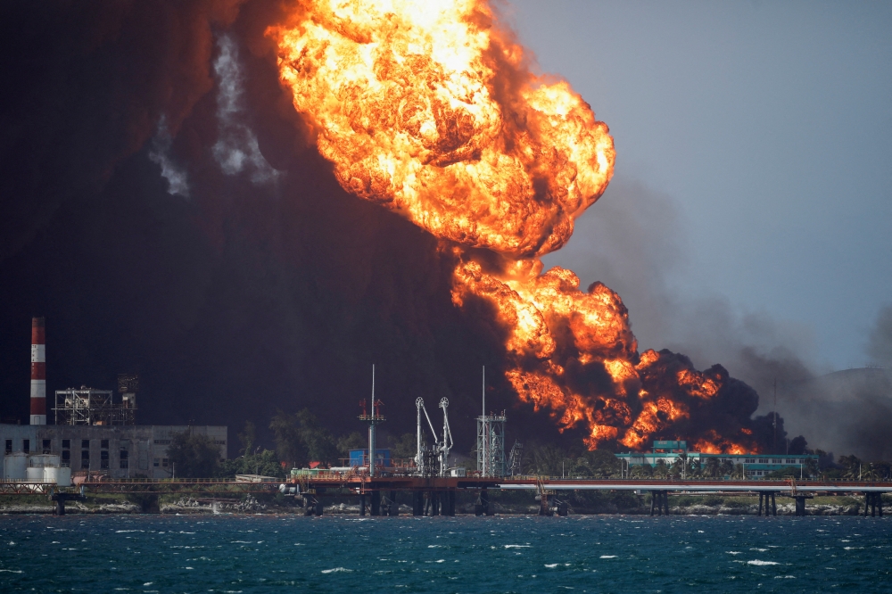 Fire is seen over fuel storage tanks that exploded near Cuba's supertanker port in Matanzas, Cuba, August 8, 2022. (REUTERS/Alexandre Meneghini)