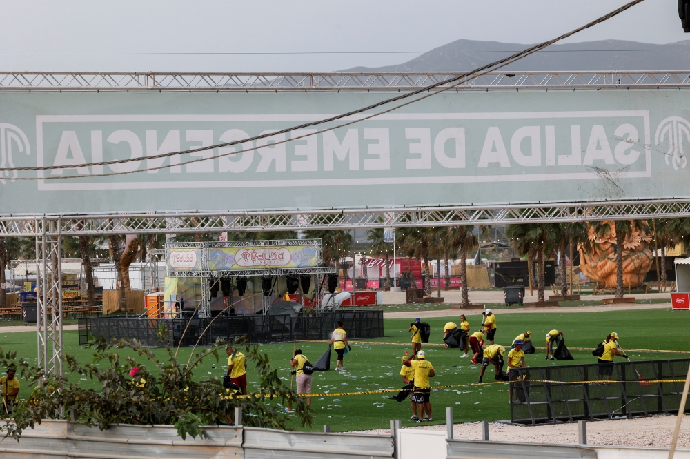 Staff members clean the venue of Medusa Festival, an electronic music festival, after high winds caused part of a stage to collapse, in Cullera, near Valencia, Spain, August 13, 2022. Reuters/Eva Manez