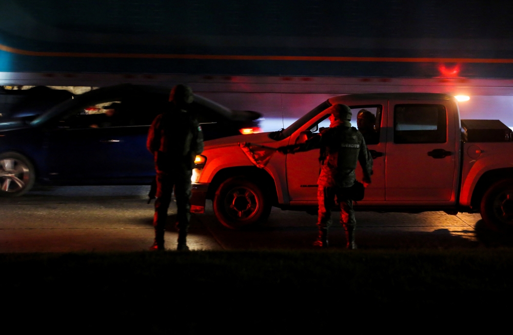 Members of security forces stand along an avenue after vehicles were set on fire by unidentified individuals in Tijuana, Baja California state, Mexico, August 12, 2022. (REUTERS/Jorge Duenes)