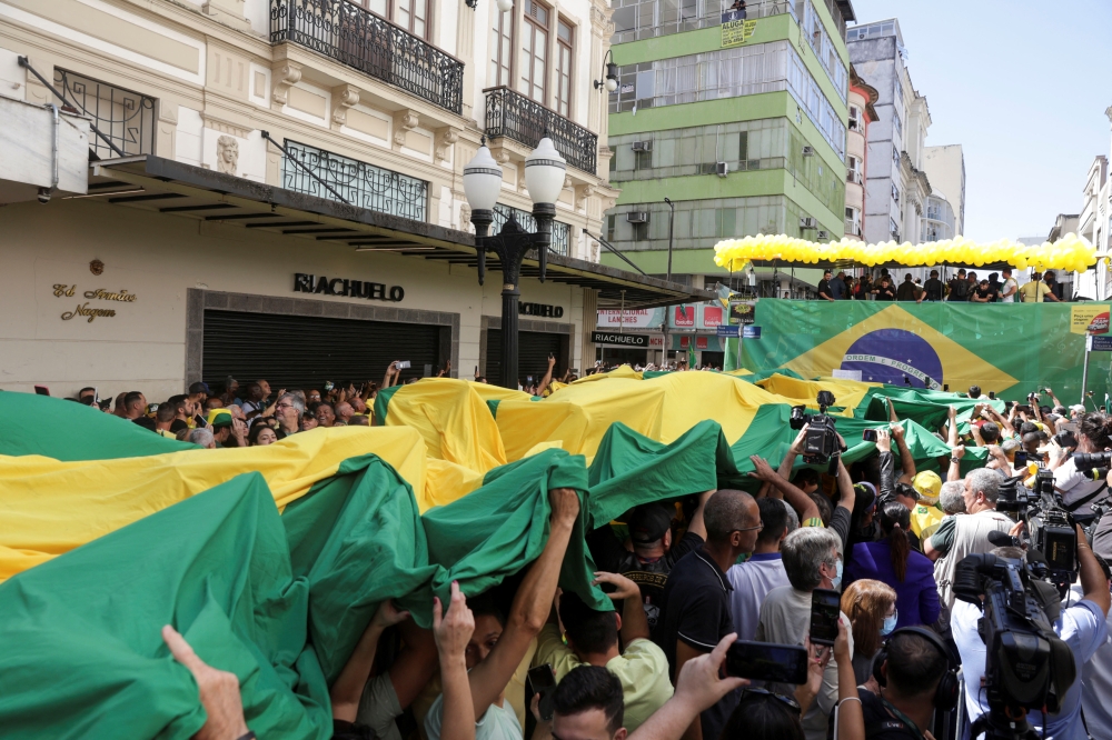 Supporters carry a flag as they attend a campaign rally of Brazil's President and candidate for re-election Jair Bolsonaro, in Juiz de Fora, Brazil, August 16, 2022. (REUTERS/Ricardo Moraes)

