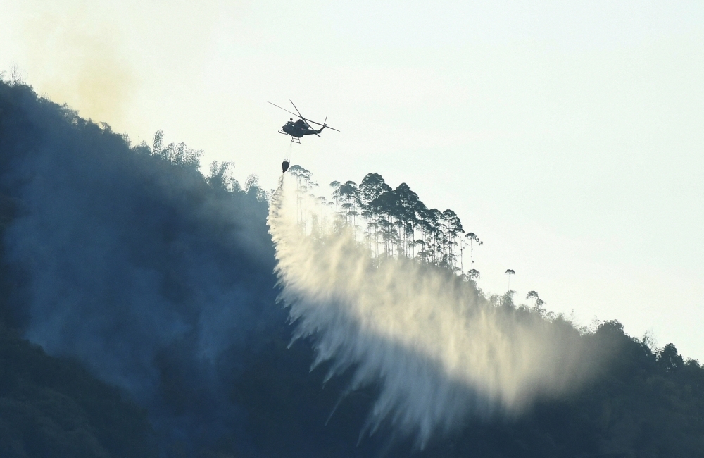A helicopter works to put out wildfire in a forest, amid hot temperature in Chongqing, China August 19, 2022. cnsphoto via REUTERS