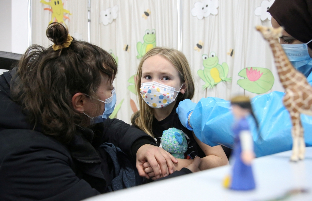 File Photo: Seven-year-old Lena Graveline-Roux has her hand held by her mother at a vaccination clinic after Canada approved Pfizer's COVID-19 vaccine for children aged 5 to 11, in Montreal, Quebec, Canada, November 26, 2021. (REUTERS/Christinne Muschi)