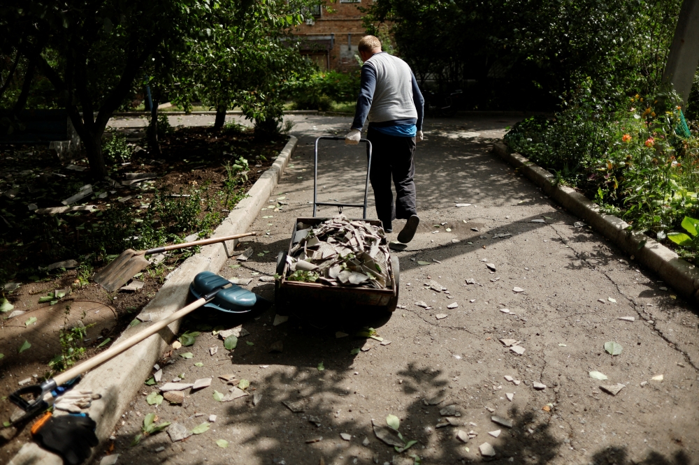 A man pulls a cart as he cleans his yard after a night shelling, as Russia's attack in Ukraine continues, in Bakhmut, Donetsk region, Ukraine August 21, 2022. REUTERS/Ammar Awad