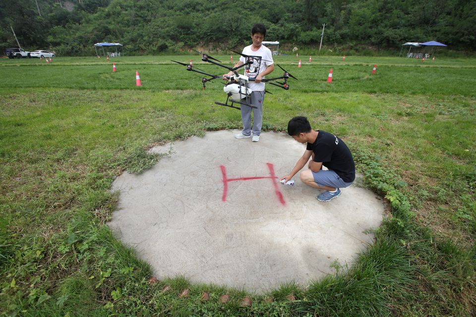 An instructor sets up landing sign as a trainee prepares to learn to fly an aerosol drone at LTFY drone training school on the outskirts of Beijing, China August 2, 2017. REUTERS/Jason Lee

