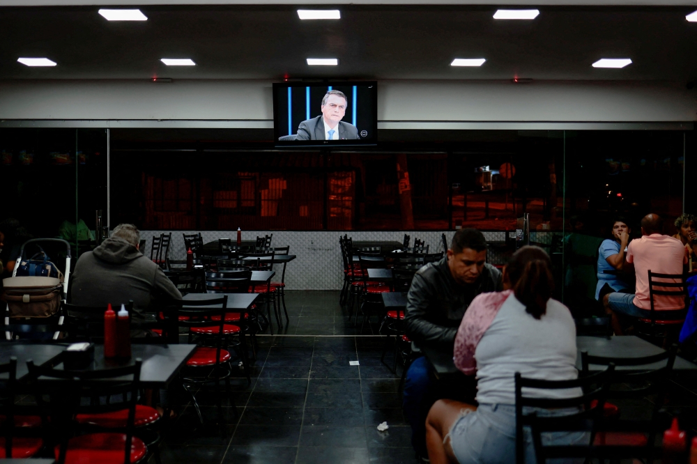 A television screen displays an image of Brazil's President and re-election candidate Jair Bolsonaro while he gives an interview on TV Globo's Jornal Nacional, at a bar on the outskirts of Brasilia, on August 22, 2022. REUTERS/Ueslei Marcelino