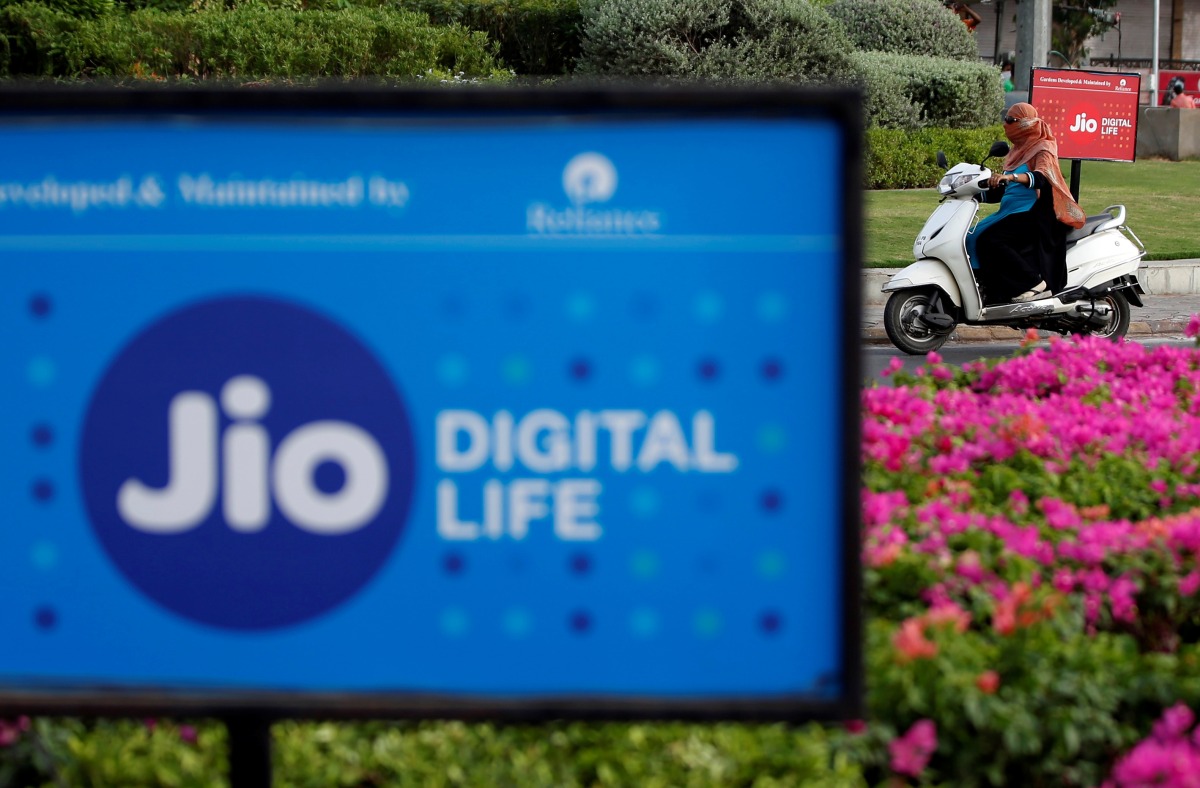 A woman rides her scooter past advertisements of Reliance Industries' Jio telecoms unit, in Ahmedabad, India, on July 5, 2018. REUTERS/Amit Dave