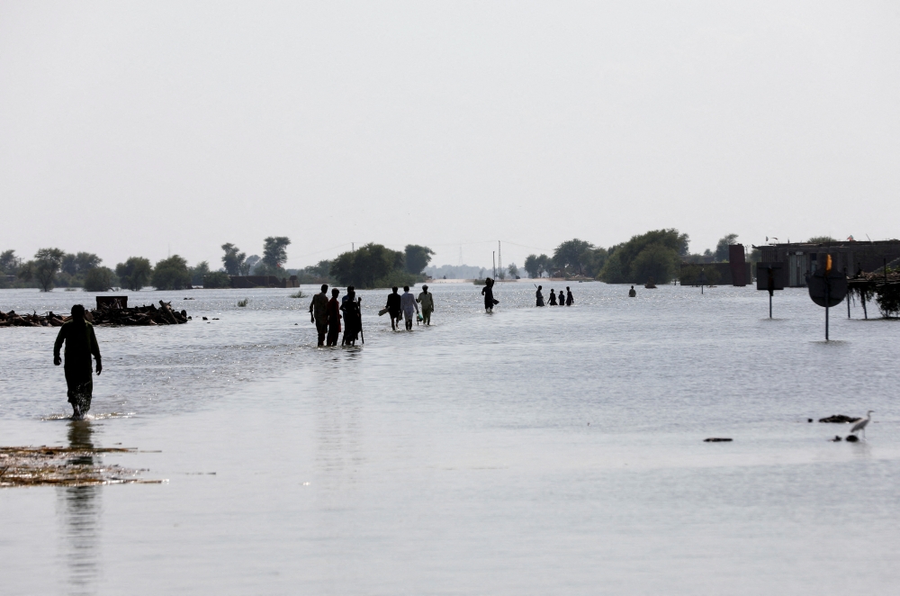 People walk amid rising flood waters on the Indus highway, following rains and floods during the monsoon season in Mehar, Pakistan August 31, 2022. REUTERS/Akhtar Soomro
