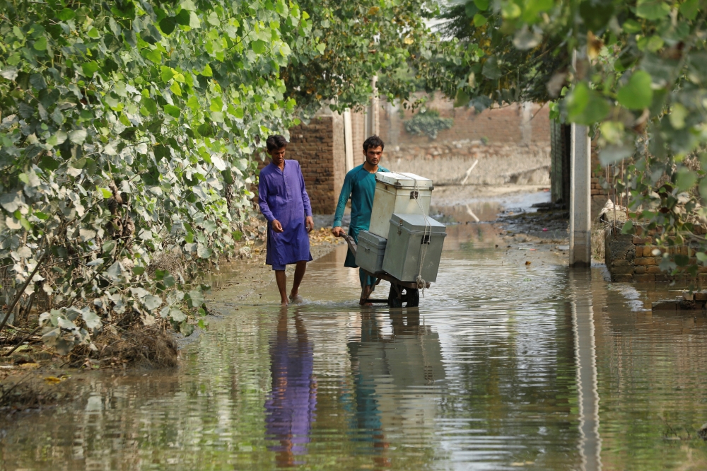 Men move their belongings as they clear up their house, following rains and floods during the monsoon season in Nowshera, Pakistan September 4, 2022. REUTERS/Fayaz Aziz